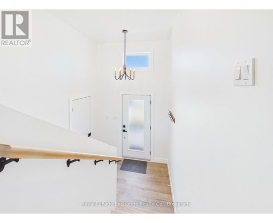 A chandelier hangs over a staircase with a glass door leading to a balcony.
