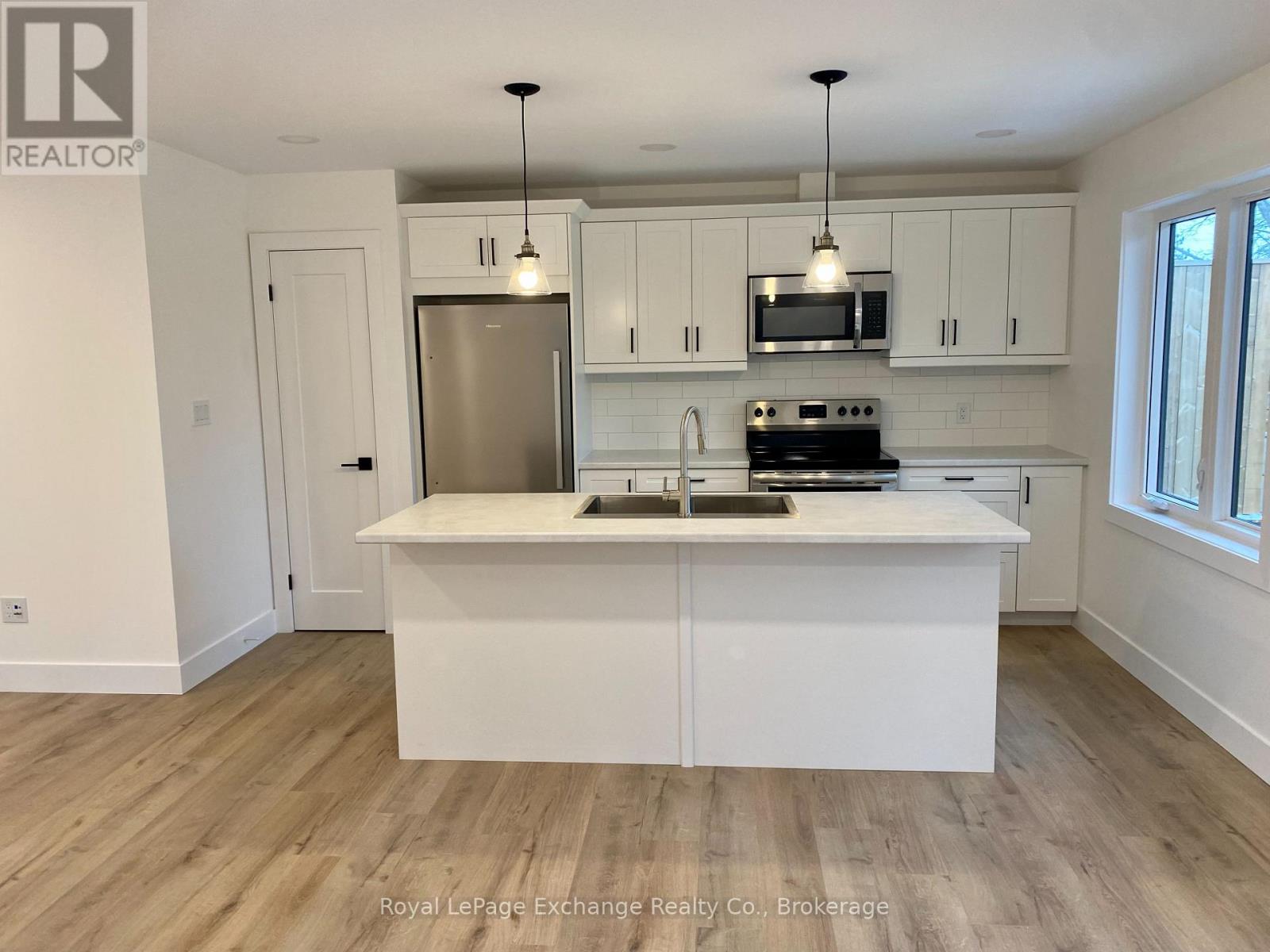 A kitchen with white cabinets and a wooden floor.