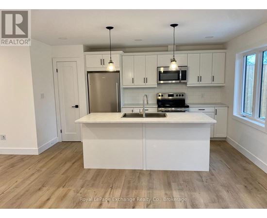 A kitchen with white cabinets and a wooden floor.
