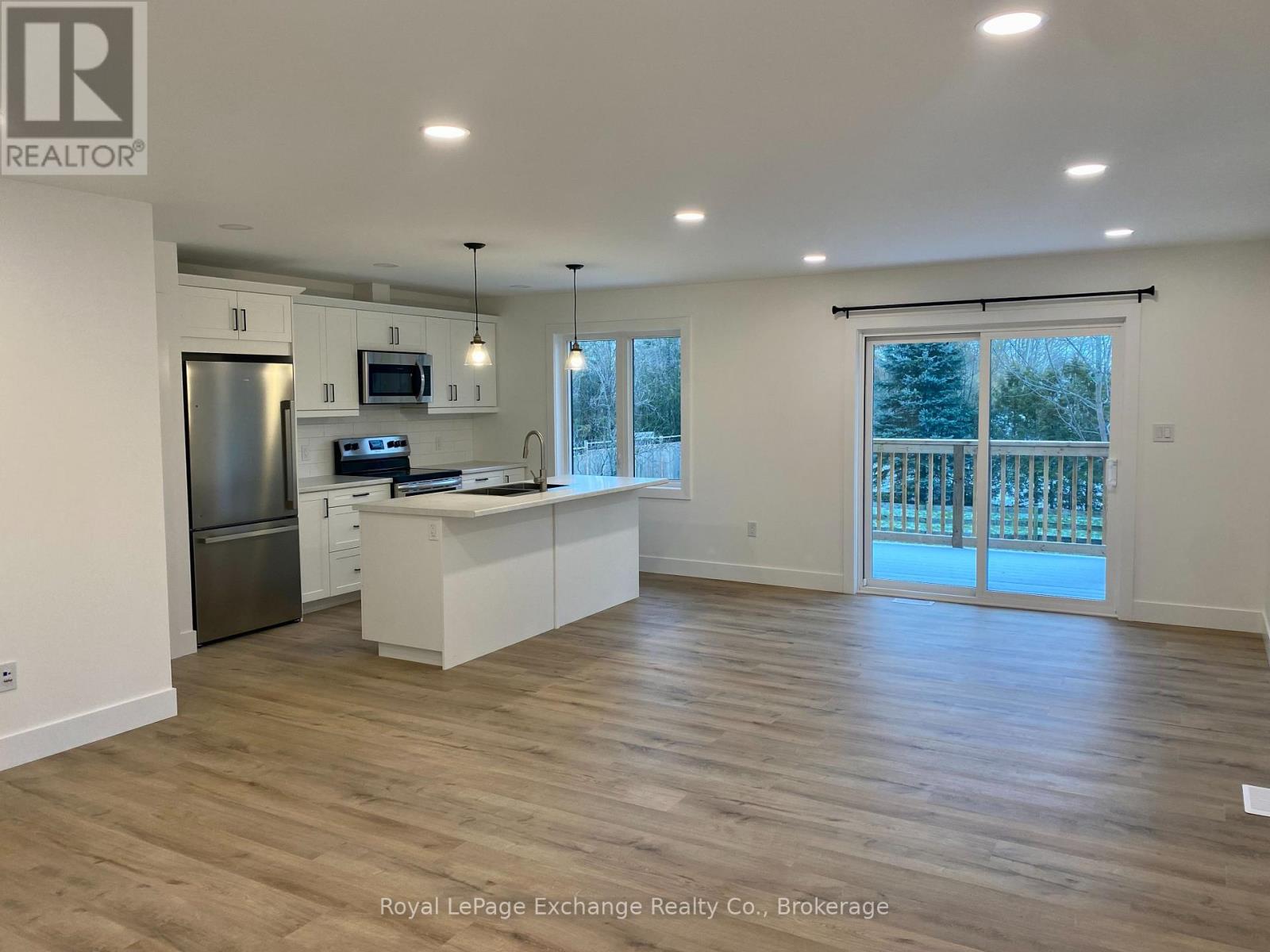 A spacious kitchen with wooden floors and white cabinetry.