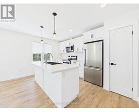 A spacious kitchen with wooden floors and white cabinetry.