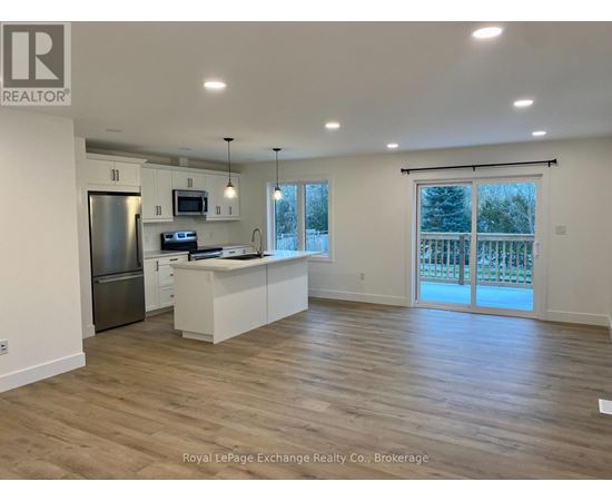 A spacious kitchen with wooden floors and white cabinetry.
