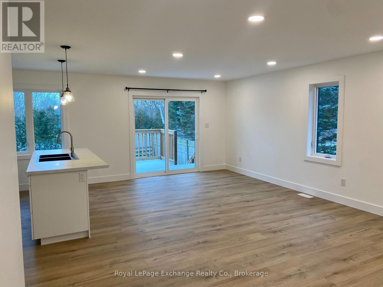 A spacious room with wooden flooring and a large window.