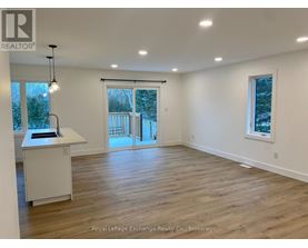 A spacious room with wooden flooring and a large window.