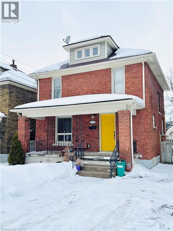 A red brick house with a yellow door and a white awning.