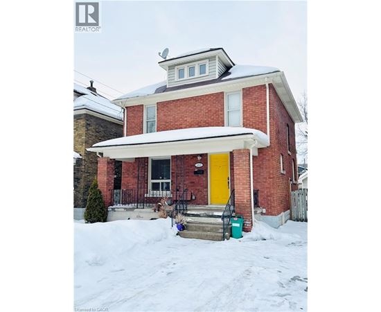 A red brick house with a yellow door and a white awning.