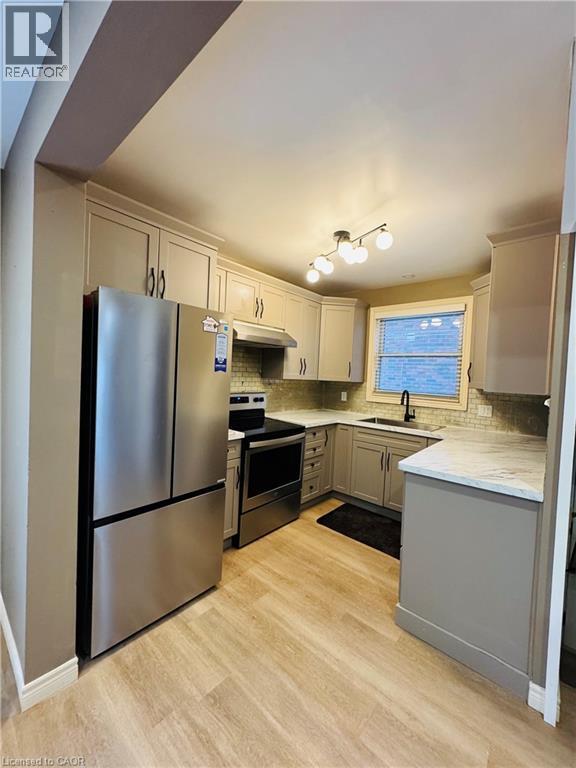 A kitchen with a refrigerator, sink, and cabinets.