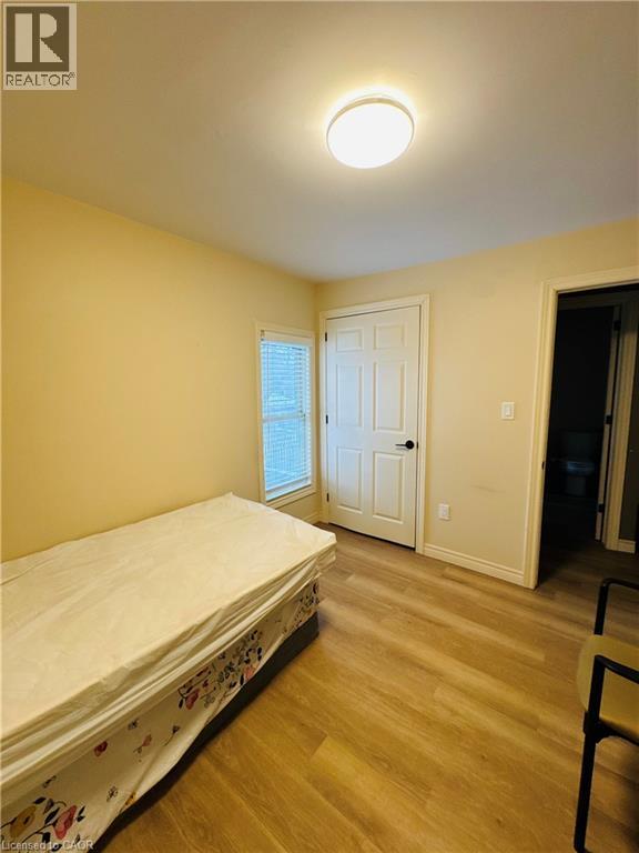A bedroom with a bed, wooden floors, and a window.