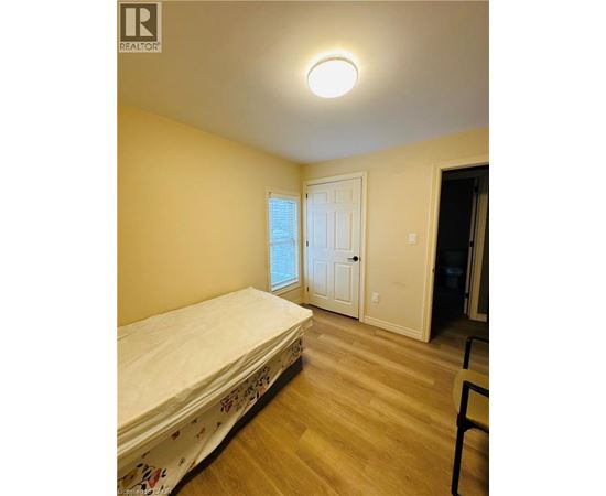 A bedroom with a bed, wooden floors, and a window.
