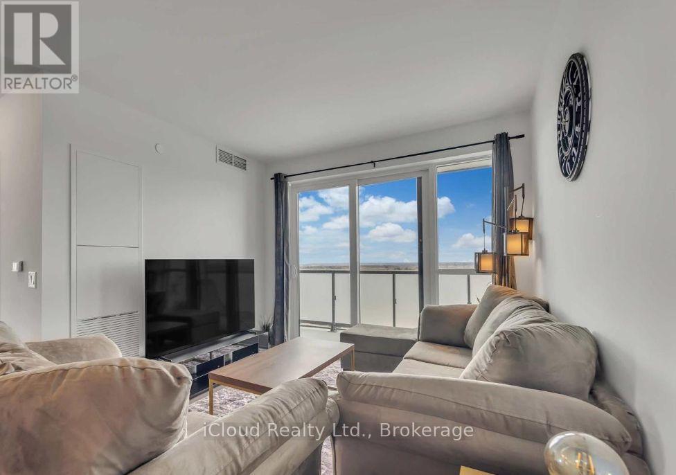 A living room with a flat screen TV and a large window with a view of the sky.