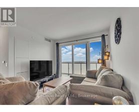 A living room with a flat screen TV and a large window with a view of the sky.