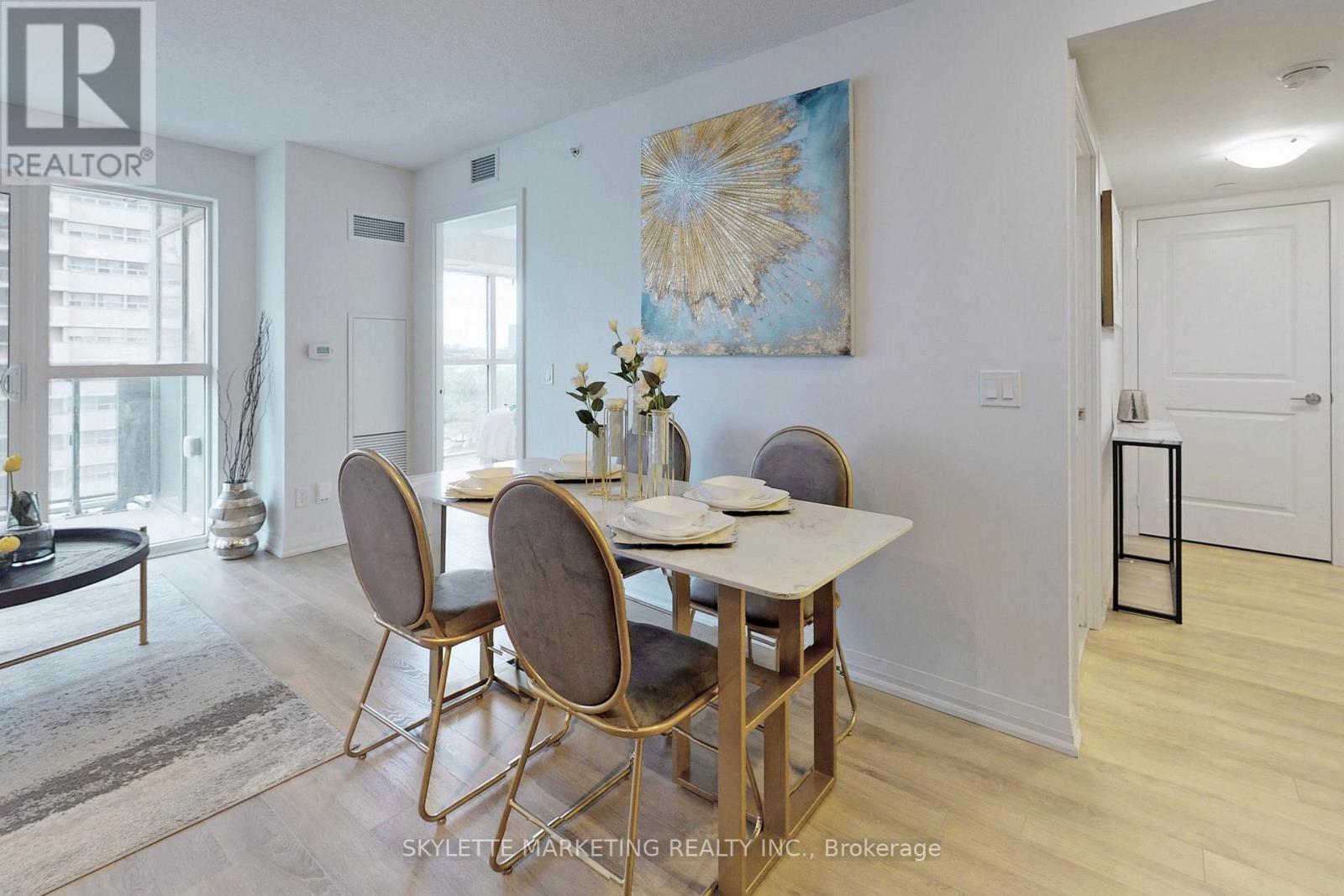 A dining room with a table set for two and a painting on the wall.
