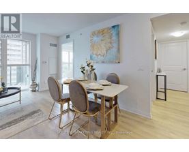 A dining room with a table set for two and a painting on the wall.