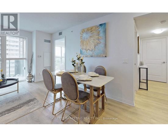 A dining room with a table set for two and a painting on the wall.