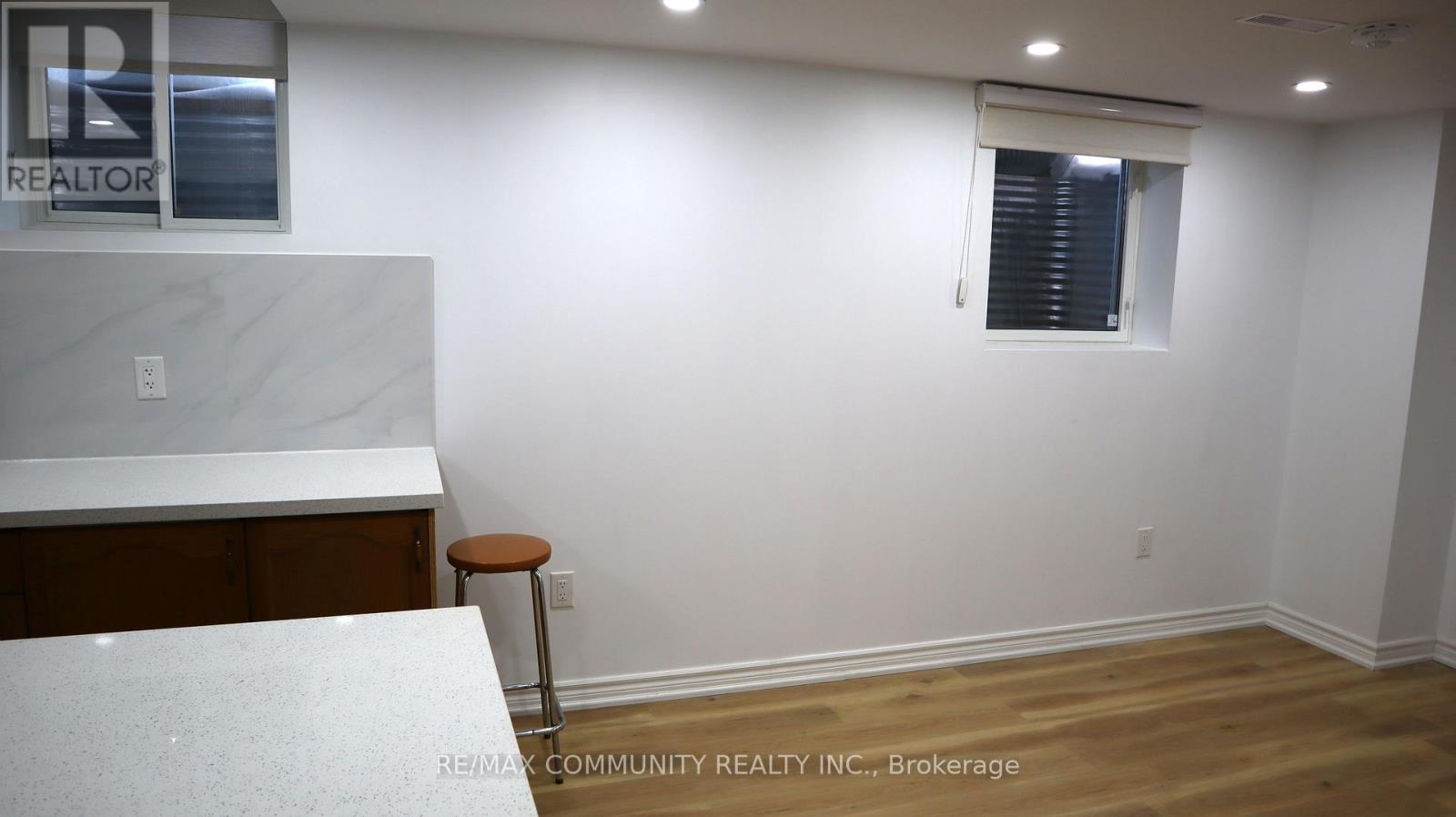 A white countertop with a stool sits in a room with a window.