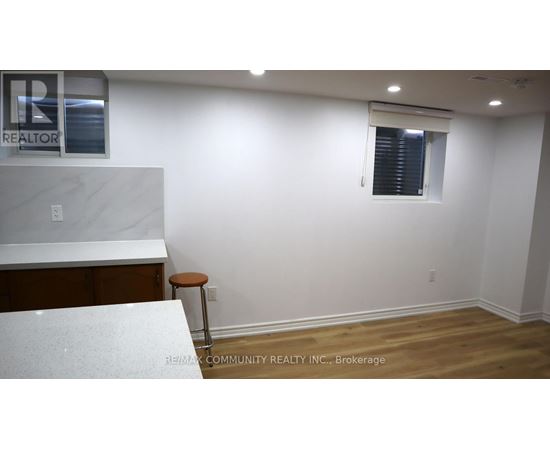 A white countertop with a stool sits in a room with a window.