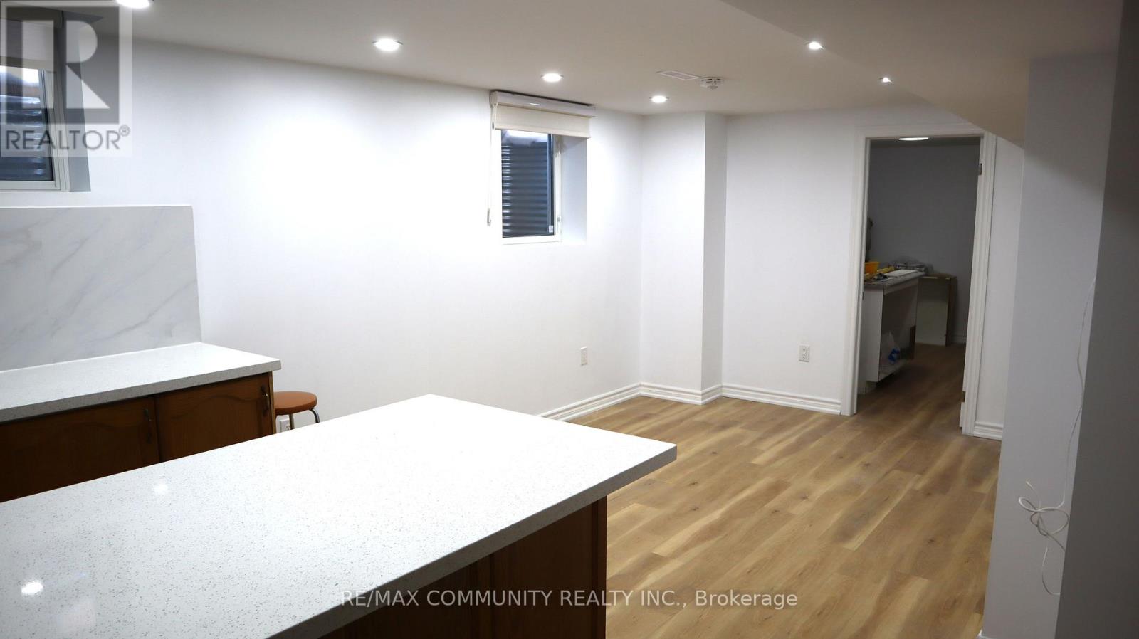 A realtor photo of a white room with wood floors and a white counter.