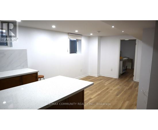 A realtor photo of a white room with wood floors and a white counter.