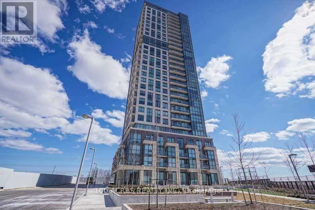 A tall, modern building with many windows is under a blue sky with clouds.
