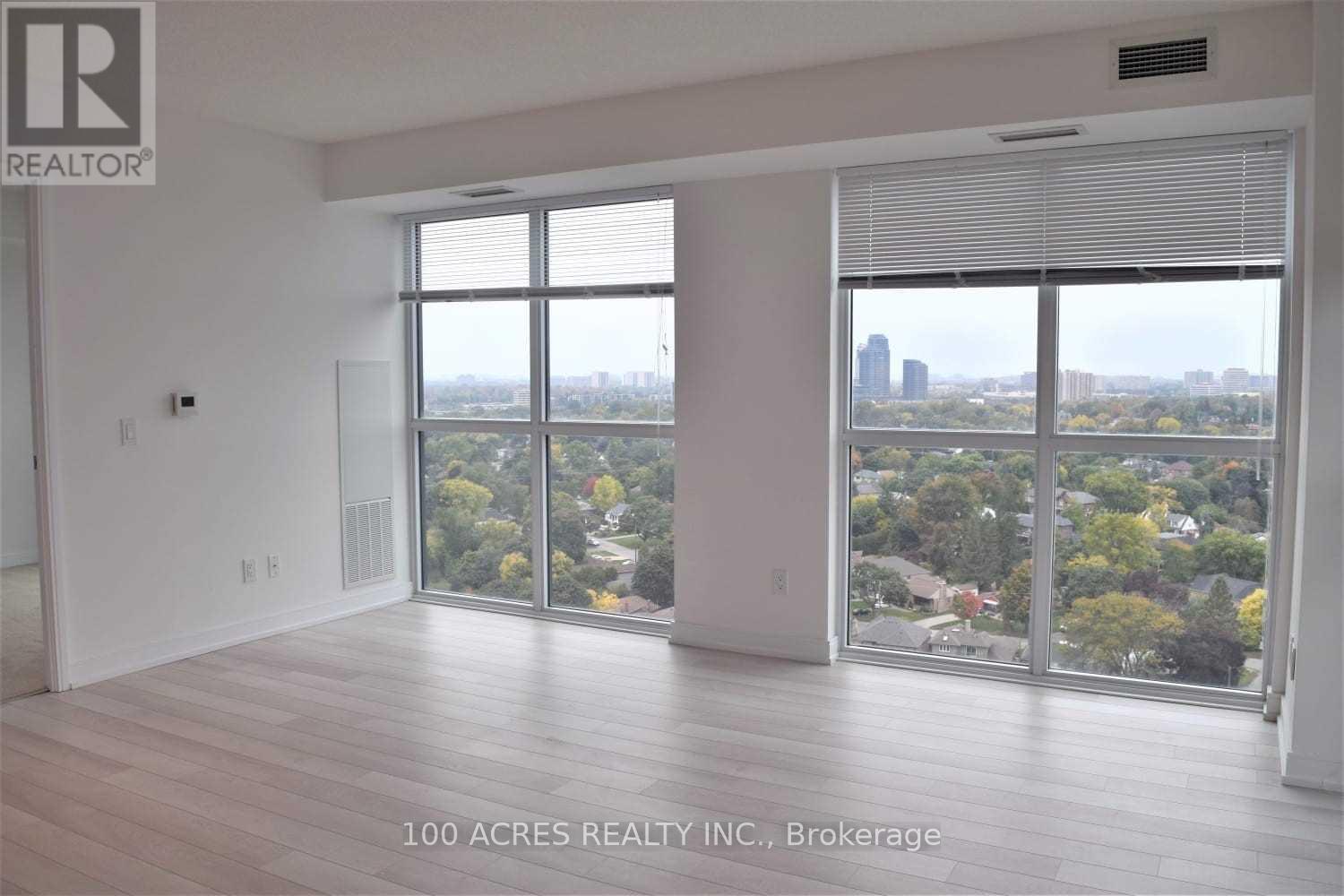 A spacious room with a view of the cityscape through large windows.
