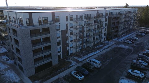A large apartment building with a parking lot in front.
