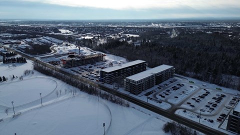 A large building complex with a parking lot in front of it.