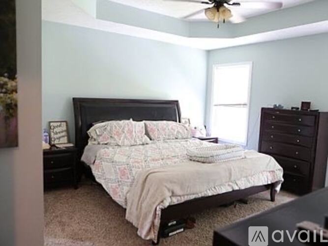 A bedroom with a bed, dresser, and ceiling fan.