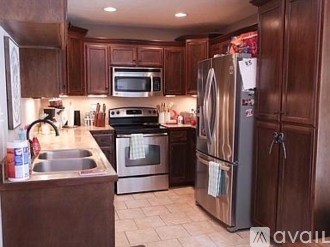 A kitchen with brown cabinets and a stainless steel refrigerator.