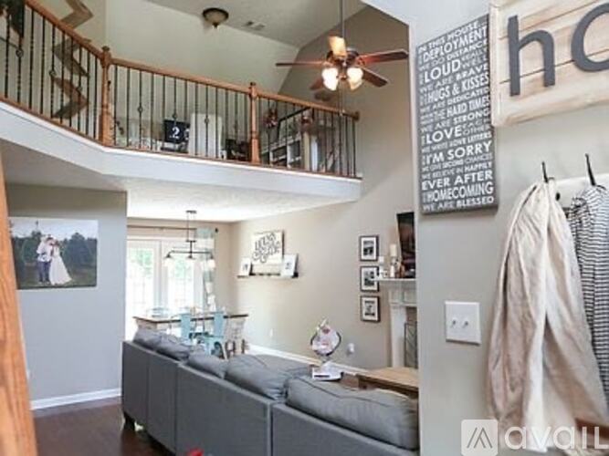 A living room with a grey couch and a wall with a word cloud on it.