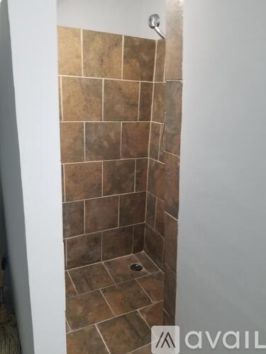 A shower with brown tiles and a white door.