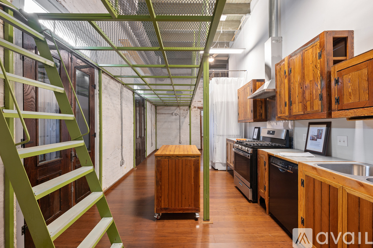 A kitchen with wooden cabinets and a green staircase.