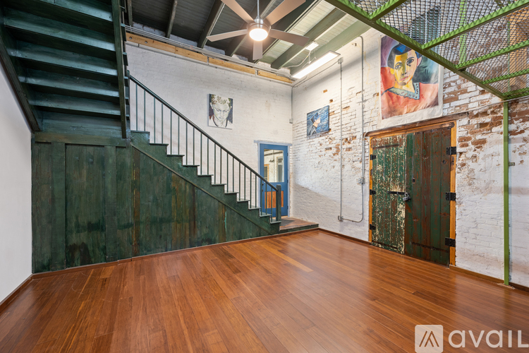 A room with a wooden floor and a staircase with a metal railing.