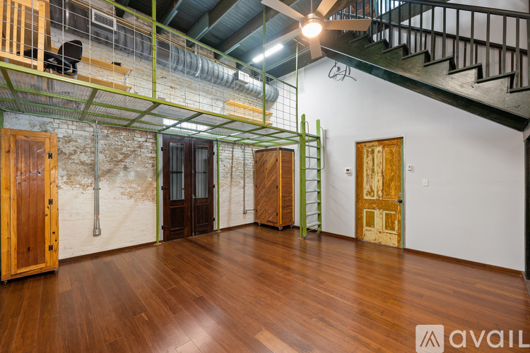 A room with wooden floors and a staircase with a metal railing.