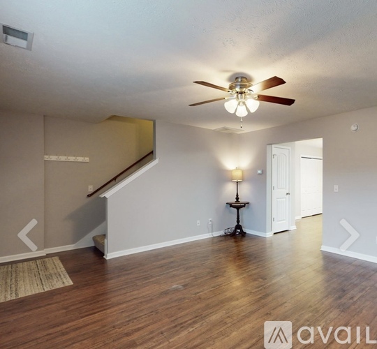 A room with a ceiling fan and a lamp on a small table.