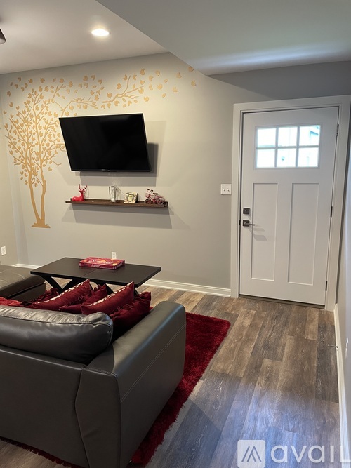 A living room with a grey couch and a tv mounted on the wall.
