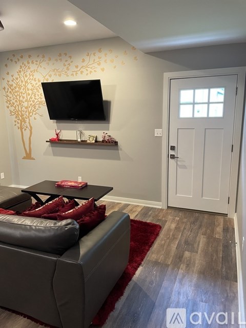 A living room with a grey couch and a tv mounted on the wall.