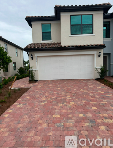 A house with a red brick pathway leading to a white garage door.