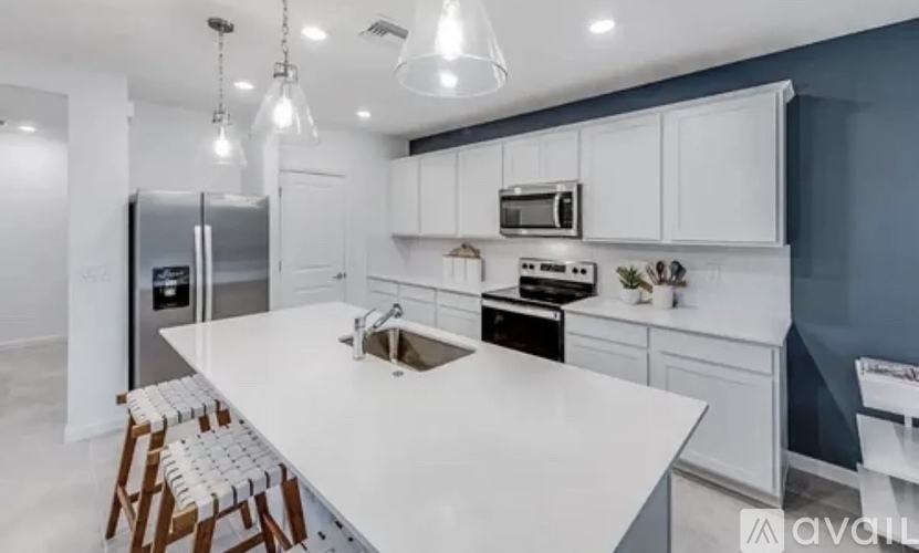 A modern kitchen with white countertops and wooden bar stools.