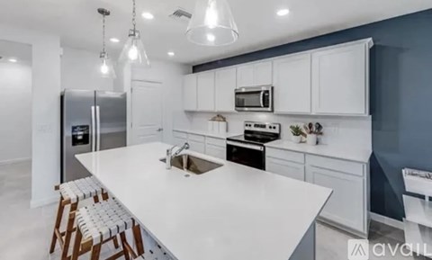 A modern kitchen with white countertops and wooden bar stools.