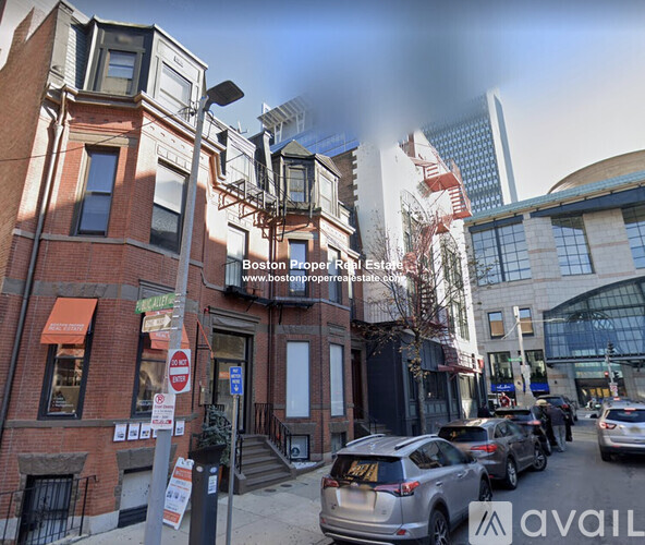 A street view of a city with cars parked on the side of the road and buildings in the background.