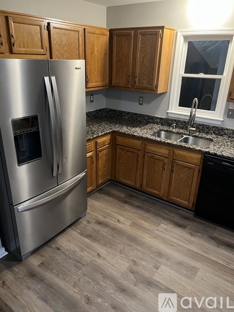 A kitchen with a stainless steel refrigerator and wooden cabinets.
