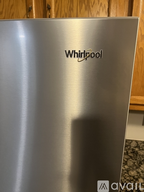 A Whirlpool brand stainless steel refrigerator with a logo on the front.