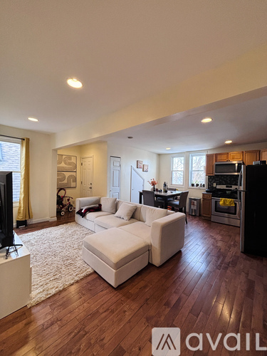 A living room with a white couch and wooden floors.