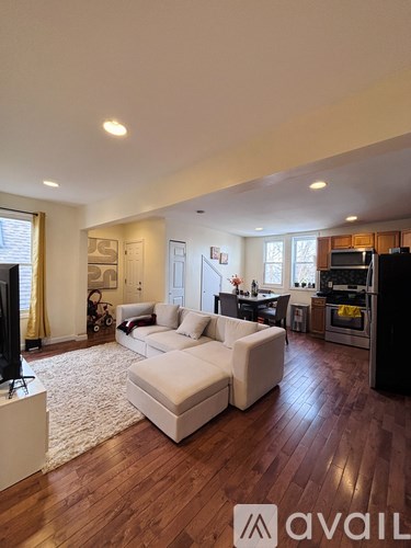 A living room with a white couch and wooden floors.