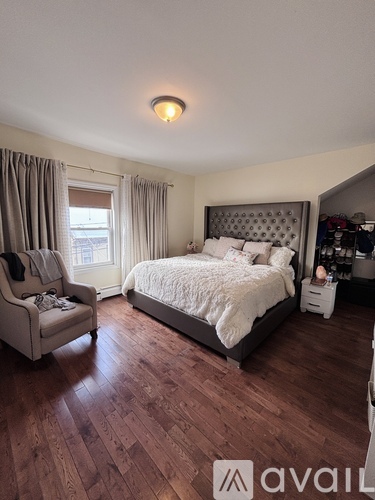 A bedroom with a large bed and a chair.