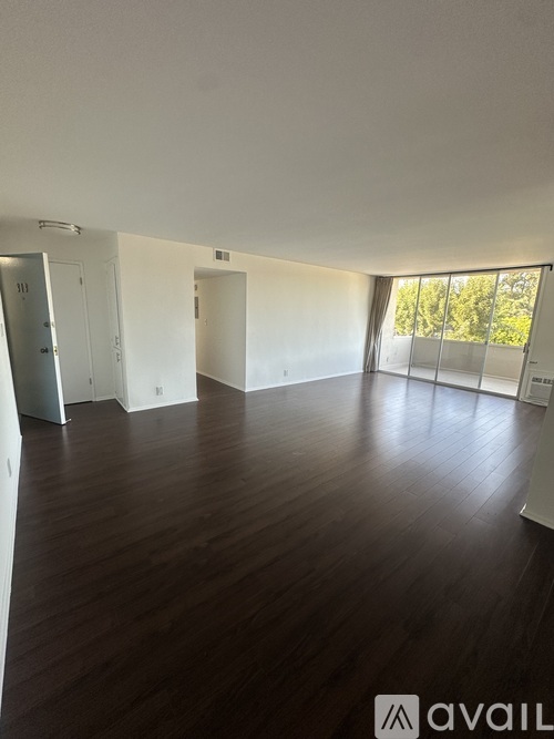 A spacious room with wooden floors and white walls.