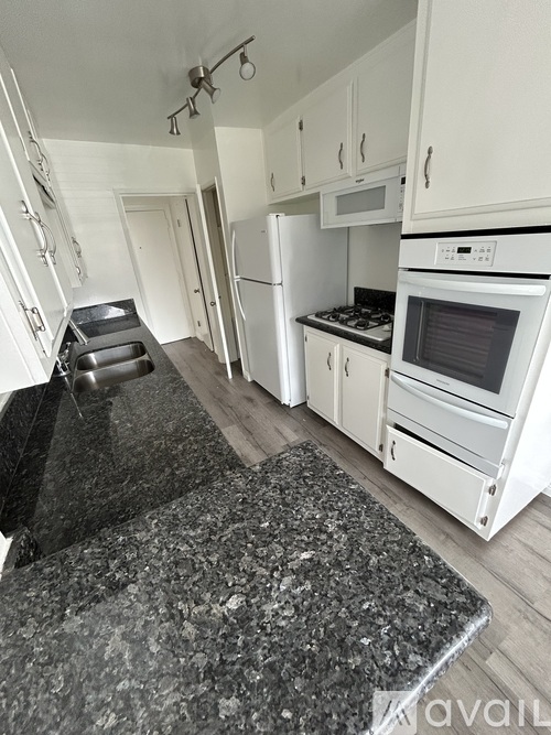 A kitchen with a granite counter top and white appliances.