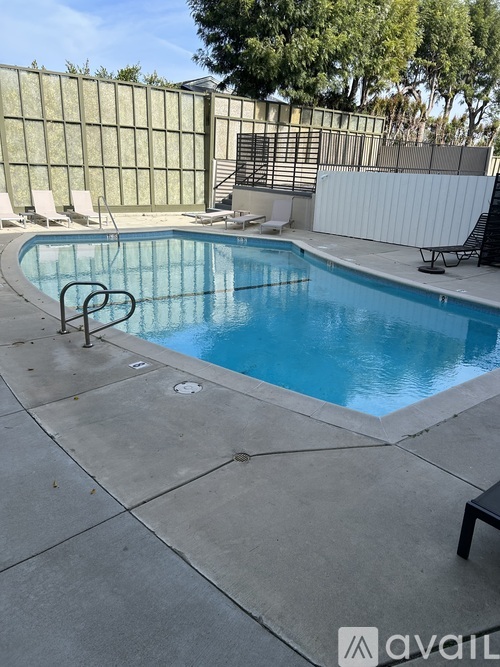 A pool surrounded by a concrete patio and a fence.