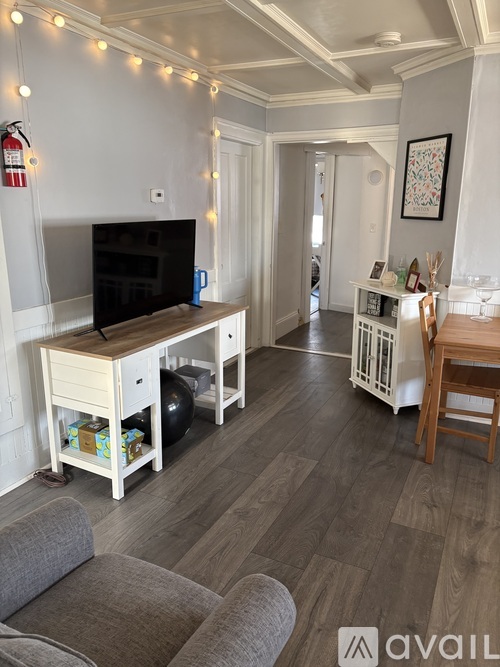 A living room with a grey couch and a wooden entertainment center.
