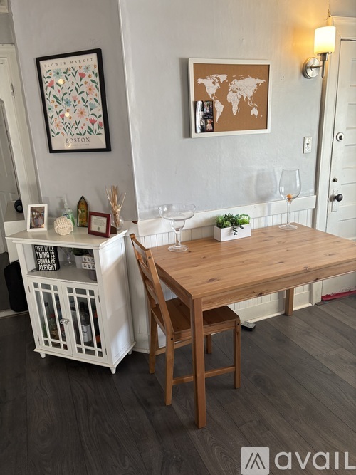 A wooden table with a chair and a cabinet with decorative items on it.